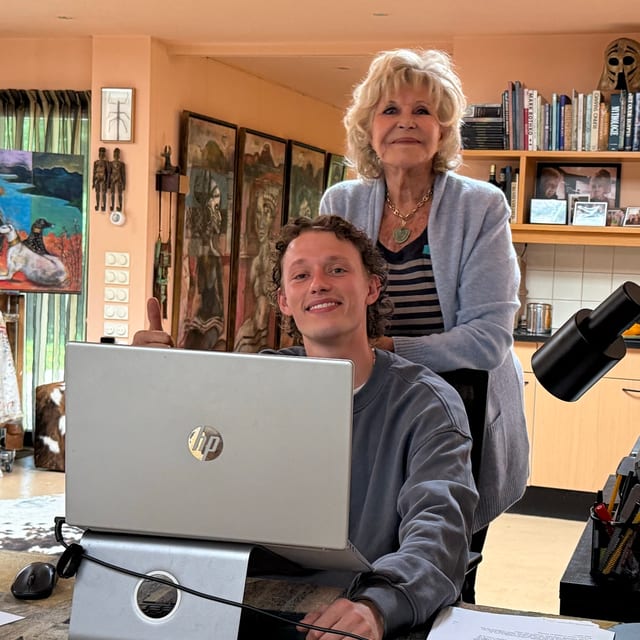 Noah achter de laptop, met Astrid Engels naast hem in haar atelier